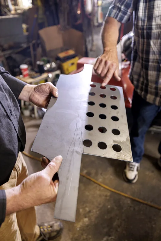 Une platine percée qui sort de la machine, tenue à deux mains